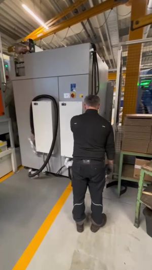 Mann arbeitet in der Nähe einer Industriemaschine in einer Fabrikumgebung