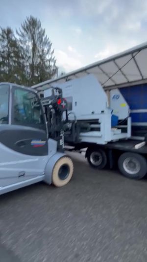 Industrial Forklift Loading Equipment Onto A Truck Outdoors