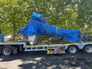 Großgeräte auf dem Lkw mit blauer Plane und Netz für den Transport gesichert