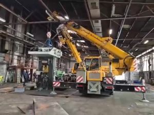 Gelber Kran hebt schwere Ausrüstung in einem geräumigen Industrielager