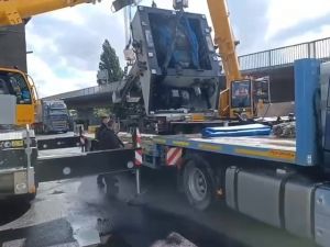 Großer Industriekran, der schwere Maschinen auf ein Transportfahrzeug auf einer Straße bewegt