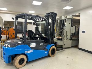 Industrial Forklift Inside Manufacturing Facility With Machinery And Equipment