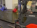 Industrial Worker Operating Forklift to Transport Heavy Equipment in Warehouse