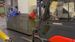 Industrial Worker Operating Forklift to Transport Heavy Equipment in Warehouse