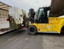 Yellow Forklift Moving Equipment Onto a Truck Platform Outdoors