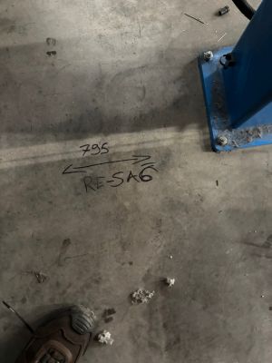 Markings Highlight Measurements on a Workshop Floor Beside Metal Base