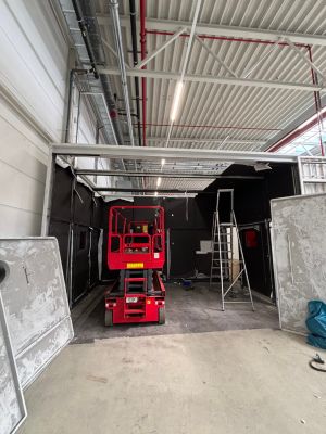 Red Scissor Lift in a Warehouse Under Construction With Exposed Ceiling Structures