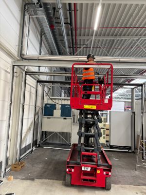 Technician Using a Scissor Lift for Pipe Installation in Industrial Facility