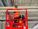 Worker on Lift Platform Performing Maintenance in Industrial Building Interior