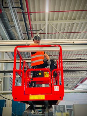 Worker on Lift Platform Performing Maintenance in Industrial Building Interior