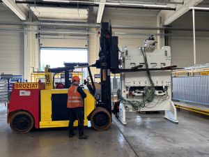 Worker Operating Forklift Inside Industrial Warehouse Lifting Large Machinery