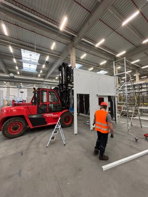 İş&ccedil;i ve Kırmızı Forkliftin &Ccedil;alıştığı End&uuml;striyel Depo Sahnesi