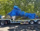 Large Equipment Secured on Truck with Blue Tarp and Net for Transport