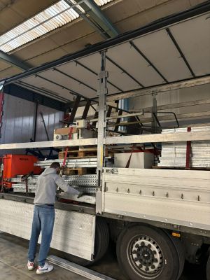 Arbeiter inspiziert offenen LKW mit Ladung in einem Lagerhaus