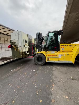 Gelber Gabelstapler, der Ausrüstung auf eine LKW-Plattform im Freien transportiert