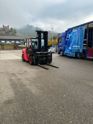 Roter Gabelstapler und offener Lastwagen in einer industriellen Außenumgebung