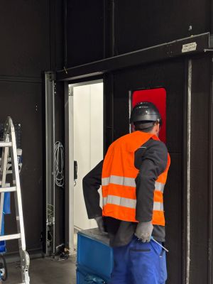 Arbeiter in Warnweste betritt Industrieanlage durch Türöffnung